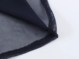 Macro shot of fine black mesh fabric showing semi-transparent honeycomb weave and stitching
