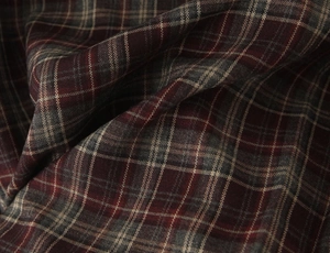 Gros plan sur un tissu écossais rouge et gris de qualité avec plis texturés