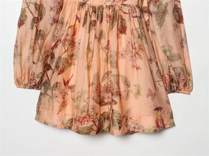 Detailed view of floral print fabric with bird motifs and pleated elastic cuffs