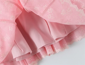 Dettaglio dell'orlo di un abito floreale rosa con pizzo delicato e tessuto a trama