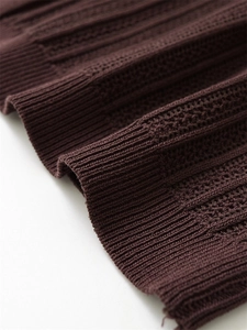 Detail of dark brown knitted fabric with ribbed texture and intricate hollow patterns
