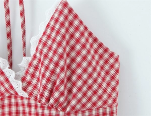 Detail of red and white gingham fabric with delicate white lace trim and straps