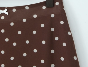 Détail d'une jupe marron à pois avec un petit nœud blanc décoratif à la taille