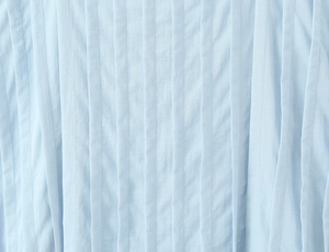 Macro shot of light blue pleated fabric with detailed vertical pin-tucks on dress