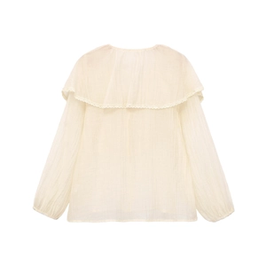 Dettaglio del colletto a balze con pizzo delicato su una camicia color crema a maniche lunghe