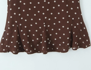 Détail du tissu à pois marron foncé avec ourlet à volants et texture mousseline légère