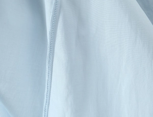 Close-up of light blue fabric texture showing fine stitching and pleated details