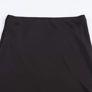 Detail of the elastic waistband on a black satin midi skirt with a smooth finish