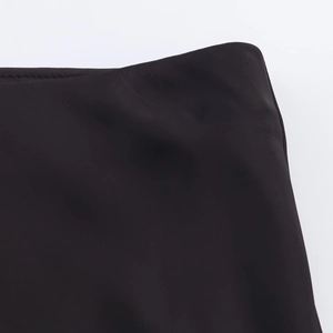 Detail of the high waist tailoring and clean stitching on a black satin midi skirt
