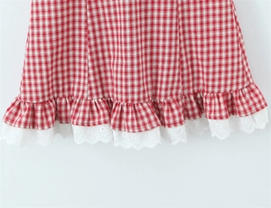 Detail of red and white plaid dress hem featuring ruffle edges and white eyelet lace