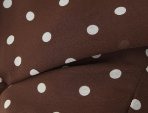 Détail du tissu en mousseline marron foncé à pois blancs montrant la texture et le drapé