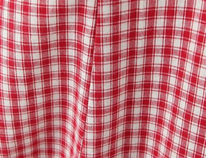 Close-up of red and white gingham fabric texture and precise stitching on the dress