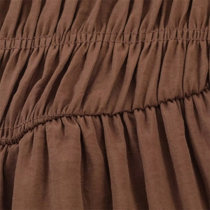 Macro shot of coffee brown fabric featuring dense smocking and elasticated gathering texture