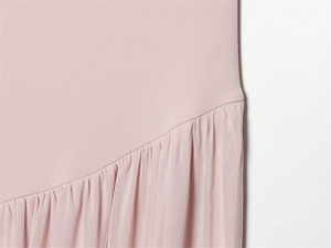 Détail de la robe rose montrant les coutures en tulle et les textures plissées
