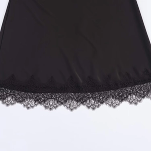 Close-up of black satin midi skirt featuring delicate eyelash lace trim at the hemline