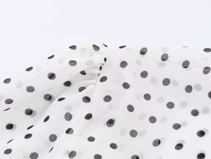 Vue macro détaillée du tissu en mousseline blanche à pois noirs et design plissé