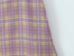 Dettaglio ravvicinato di tessuto scozzese vintage viola, beige e rosso con trama fine