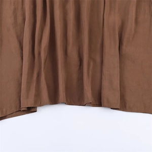 Close-up of caramel brown midi dress hem showing fine stitching and draped fabric texture