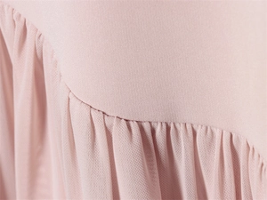 Détail d'une robe rose montrant le tissu en maille plissée et la texture lisse