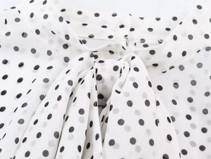 Détail d'un chemisier à pois avec un col élégant noué en forme de nœud gracieux