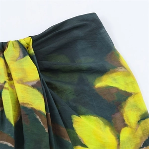 Gros plan détaillé du tissu vert foncé de la jupe avec motifs floraux jaunes et marrons