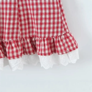 Red plaid dress hem with pleated ruffles and white lace trim detail in close-up
