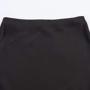 Close-up of the high-waist design on a black satin midi skirt with smooth lace textures