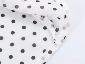 Détail du motif à pois noirs sur tissu mousseline blanc avec coutures et finitions précises