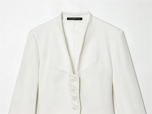 Close-up of white blazer collar with ZEAL WOMAN brand label and four buttons