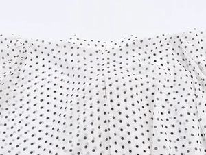 Détail du bouton au col arrière et du motif à pois sur cette chemise cape en mousseline