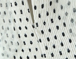 Close-up of white mesh dress with black polka dots, smocking texture and hidden zipper
