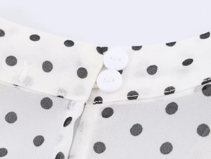 Détails de l'encolure à double bouton avec motif à pois noirs sur tissu en mousseline