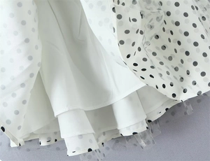 Close-up of white polka dot mesh fabric layers and hemline detail on a mini dress