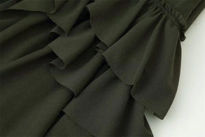 Detailed close-up of dark green layered ruffles and textured fabric on the dress