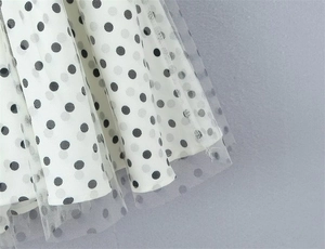 Close-up of double-layered mesh fabric with elegant black polka dots on white tulle