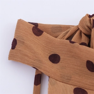Detail of brown polka dot dress fabric showing soft pleats and lightweight chiffon texture