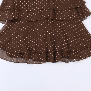 Detailed view of layered ruffles and white polka dots on brown chiffon fabric hem