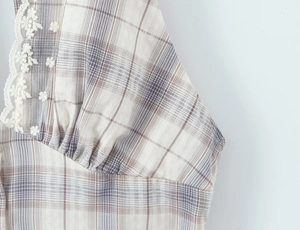 Détail de robe à carreaux avec broderie en dentelle florale et tissu froncé