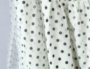 Detail of white mesh fabric with black polka dots and layered pleated tulle texture