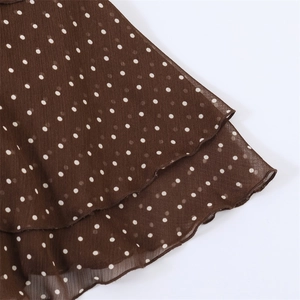 Detail of dark brown polka dot chiffon dress with tiered ruffle hem and pleated texture