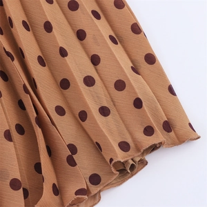 Detail of brown polka dot pleated chiffon skirt fabric with fine vertical pleats