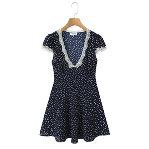 Detail of V-neckline with white lace trim and pink floral accent on polka dot dress