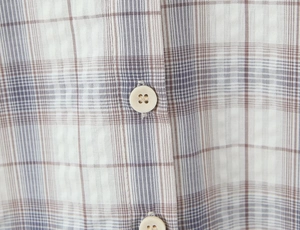 Gros plan de deux boutons beiges sur un tissu à carreaux marron au style vintage chic