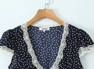Detail of V-neckline with delicate white lace trim on a navy blue polka dot blouse