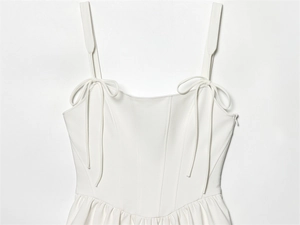 Detail of white corset top featuring adjustable tie straps and boning stitching details