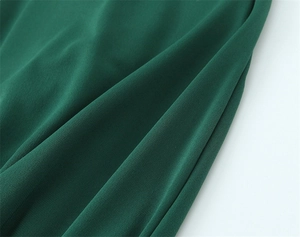 Gros plan détaillé du tissu en maille vert foncé avec texture douce et drapé élégant