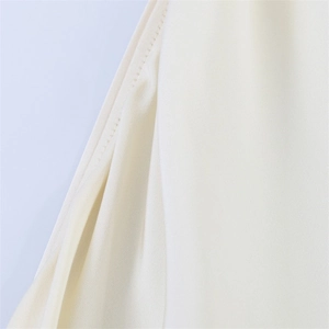 Detail view of precise side seam stitching on cream white sexy halter neck long dress