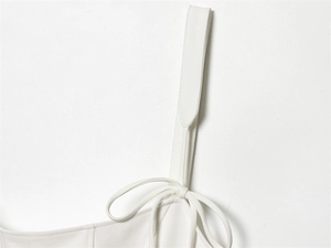 Detail shot of a white fashion top featuring wide shoulder straps with decorative bow ties