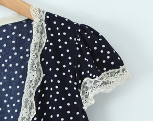 Detail of navy blue polka dot dress featuring delicate white lace trim and puff sleeves