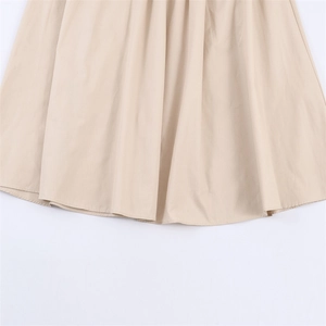 Détail de l'ourlet de robe beige montrant les coutures et la texture du tissu en coton